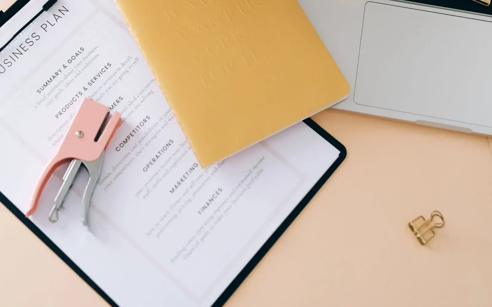 Business planning clipboard and stationery next to an open laptop